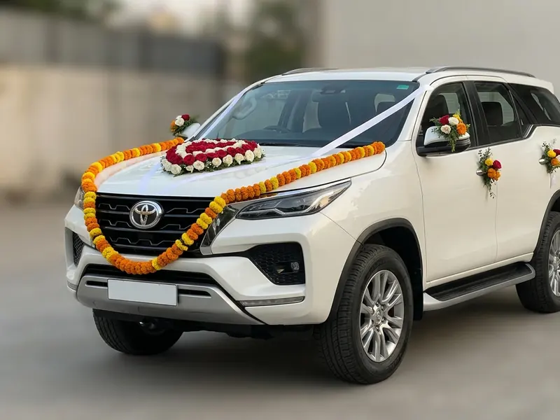 White Toyota Fortuner decorated with marigold garlands and red roses for a wedding in Ahmedabad