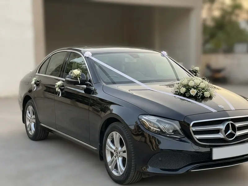 Black Mercedes-Benz E-Class decorated with white roses and ribbon for a wedding in Ahmedabad